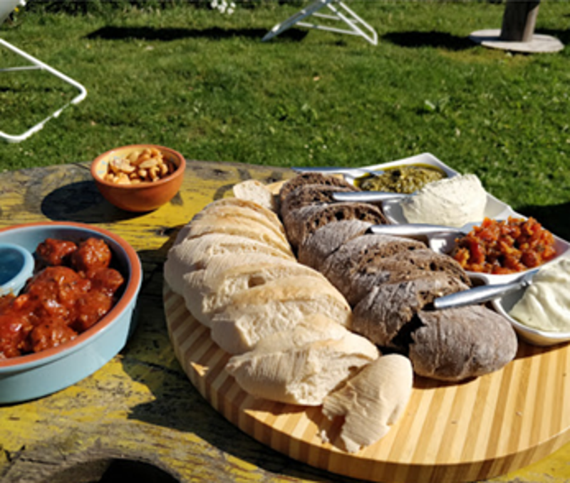 Een deelplank met brood, dips en gehaktballetjes in het gras